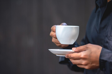 Asian man holding hot coffee in paper mug cup to sniff smell of espresso in morning sunlight. man carry coffee break to sniff fragrant smell the aroma of coffee and work.