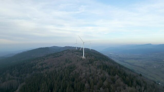 Vue a&eacute;rienne sur un parc &eacute;olien avec des sapins et ciel bleu un peu couvert 2