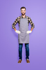 Full size body portrait of attractive cheerful carpenter with hairstyle in safety glasses, jeans, looking at camera holding his two arms on waist isolated on grey background