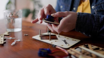 Robotic school project: Young student building robot vehicle at artificial intelligence programming class - STEM education concept - Focus on right hand holding wood piece - Powered by Adobe