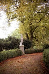 White statue amongst autumn leaves on the Waddesdon estate in autumn.