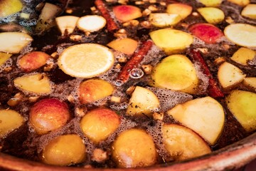 Closeup shot of traditional mulled wine with cinnamon sticks, oranges, and apples.