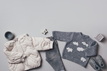 Fashion children's clothing, shoes (knitted sweater, jeans, boots, toy rainbow). Outfit for little boy. Winter, autumn collection. Organic cotton. Top view, flat lay. Copy space