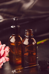 Wellness drop liquid pipettes oil, hyaluronic acid, bakuchiol, serum elixir. Aesthetic dropper glass bottle Mock-Up among flowers. Korean beauty concept.