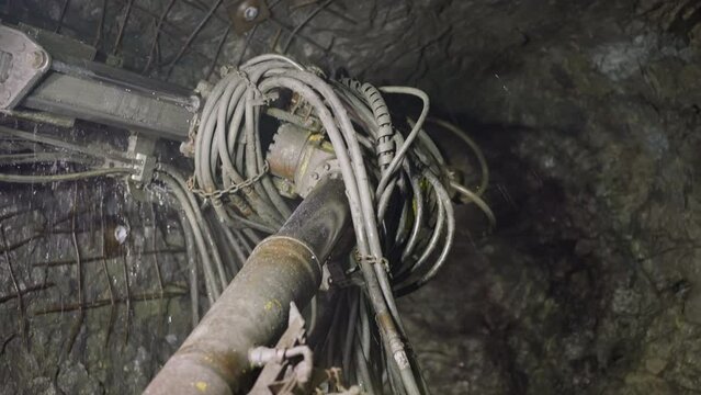 Machinery equipment drills holes for setting explosives in ore mine. Professional robot drill with coolant operates to mine minerals closeup
