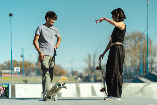 Skater boy and girl talking in the middle of the skate park