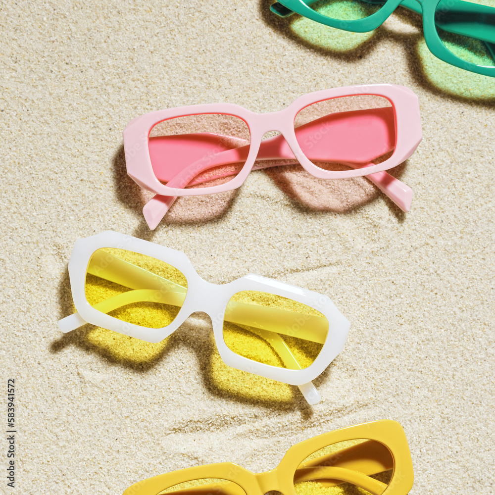 Wall mural set of colorful sunglasses on beach sand background at sunlight with shadow. summer fashion eyeglass