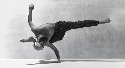 Black and white image, monochrome. Standing at one hand. Bearded strong man training shirtless,...