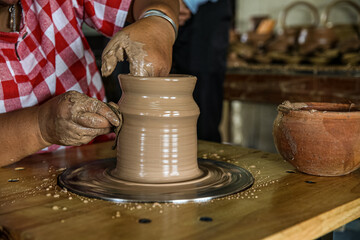 Potter creates an earthen bowl. The potter's fingers shape the clay inside and outside.Workshop place