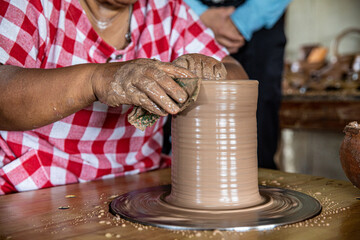 Potter creates an earthen bowl. The potter's fingers shape the clay inside and outside.Workshop place