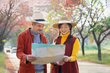 senior man father and young woman daughter standing by the street,find a location on a map for travel in the city