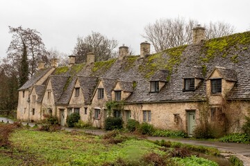 Fototapeta na wymiar Road running alongside a row of historic quintessential Cotswold cottages in Bibury, England