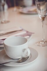 Selective focus shot of an empty white tea cup with spoon on a table laid for English afternoon tea