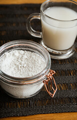 Diatomaceous earth also known as diatomite mixed in glass of water, good for human body detox concept. Jar and glass with healthy drink on home kitchen table.
