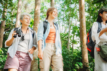 woman family walking in the forest to watching a bird in nature, using binocular for birding by looking on a tree, adventure travel activity in outdoor trekking lifestyle, searching wildlife in jungle