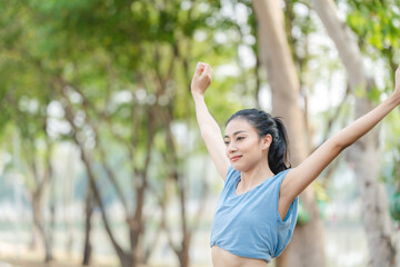 Asian woman stretching body and neck after jogging exercise at park in the city. Attractive athlete girl in sportswear enjoy outdoor lifestyle sport training fitness running workout in morning summer