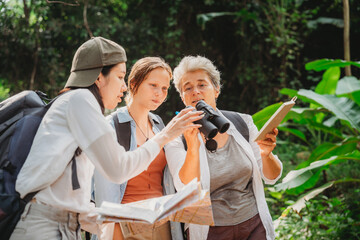 woman family walking in the forest to watching a bird in nature, using binocular for birding by looking on a tree, adventure travel activity in outdoor trekking lifestyle, searching wildlife in jungle