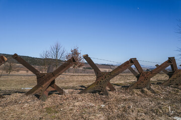 Iron anti-tank, czech hedgehog, obstacles in the meadows with the mountain range of the Kralicky Sneznik in the background. Lichkov, Pardubice region, Czech republic.