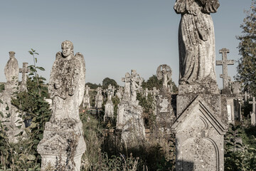 Old cemetery. Ancient abandoned graves with statues, overgrown with moss and lichens. Special color effect