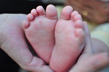 Obraz na płótnie Canvas a person holding a baby with their feet 