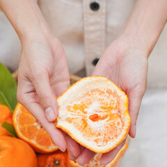 Cut part of orange fruit in human hands