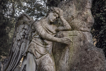 Fototapeta na wymiar Angel draws a cross on a stone. Old beautiful stone statue (faith concept)