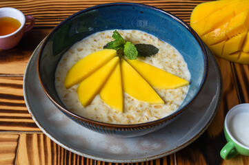 Oatmeal served with mango on a wooden table close up