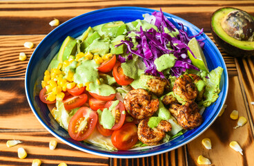 Shrimp salad with avocado, tomatoes, cabbage and sauce close up side view