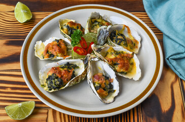 Oysters baked with 3 cheeses on white plate close up