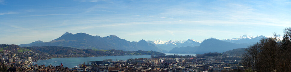 Fototapeta na wymiar Wide angle aerial view of famous Swiss City of Luzern with Reuss River, Chapel Bridge, Lake Lucerne and Swiss Alps on a sunny spring day. Photo taken March 22nd, 2023, Lucerne, Switzerland.