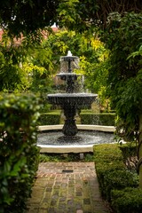 View of old fountain streaming in cozy garden