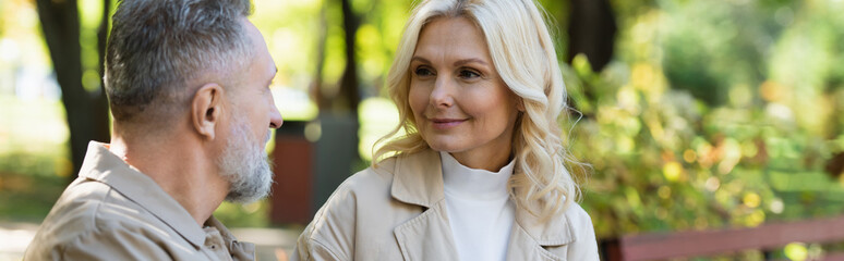 Positive mature woman looking at husband in spring park, banner.