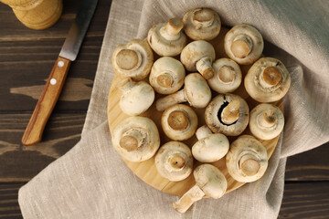 fresh large fragrant champignon mushrooms in a dark kitchen next to a knife and pepper shaker. for labels splash screens menu banners shop signs