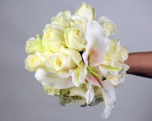 Hand holding a bouquet of fresh yellow roses