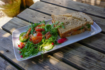 delicious wholemeal bread sandwich on plate with salad garnish. lunch food in pub garden 