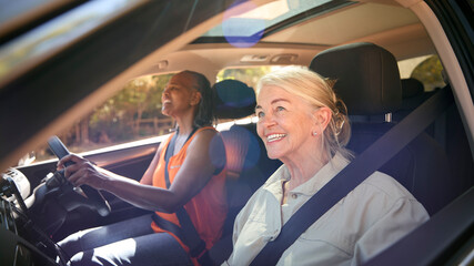 Two Senior Female Friends Enjoying Day Trip Out Driving In Car Together