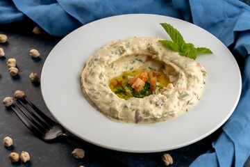 Fototapeta premium Closeup shot of Hummus Beiruti with vegetable ingredients on a white plate