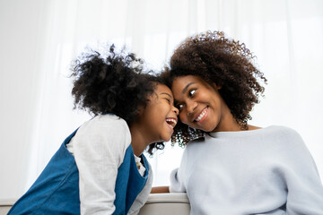 Obraz premium Nice girl and her mother enjoy sunny morning. Good time at home. Child giving card flower for her mom. Family playing on sofa.