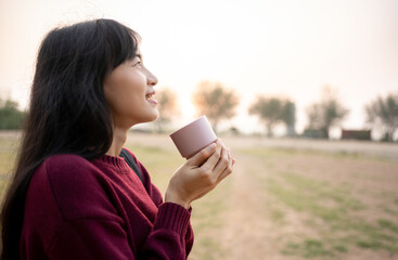 Asian Woman drinking hot coffee outdoor enjoying landscape during holiday on the mountain with rim...