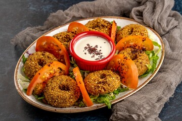 Closeup shot of Falafel balls served with white sauce and tomatoes, cold appetizer
