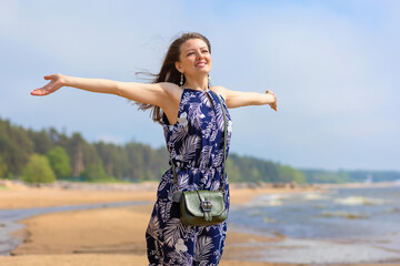 young beautiful woman, girl on beach breathing fresh air, turning her face to sun and wind. concept of freedom, vacation, travel
