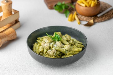 Appetizing plate of penne pasta with freshly sliced zucchini served in a gray bowl