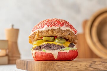 Delicious beef burger with cheese and onion ring served on a wooden cutting board