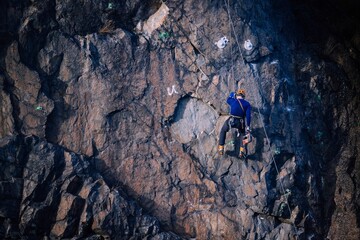 Man Top Rope Climbing on the big rock with the blue sky in the background