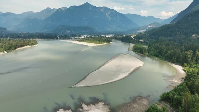 Aerial slow movement around Fraser river surrounded by dense trees in Canada