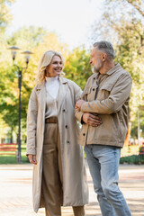 Smiling mature couple talking while walking in spring park.