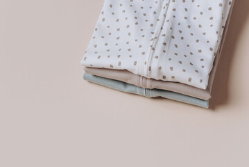 Set of organic cotton bodysuit, romper on beige background. Baby clothes. Fashion newborn clothes. Flat lay, top view. Copy space. Banner