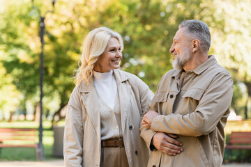 Fototapeta premium Happy blonde woman looking at husband while spending time in park.