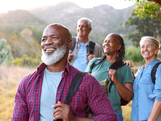 Fototapeta premium Group Of Senior Friends Enjoying Hiking Through Countryside Together