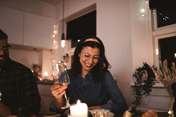 Young woman laughing and drinking wine during a dinner party